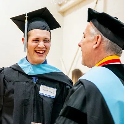 student and professor in academic robes at graduation