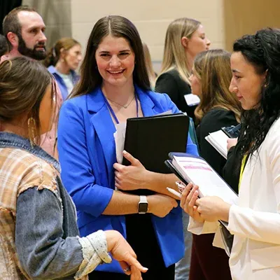 a student holding a binder smiles during the career fair event