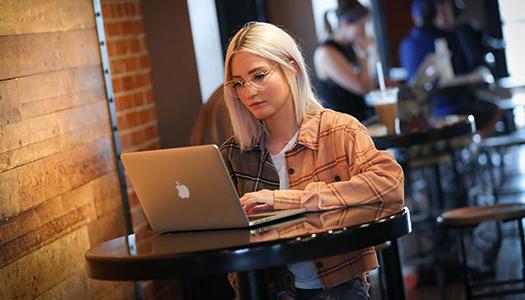 a woman sits at a table in a coffee shop with her laptop